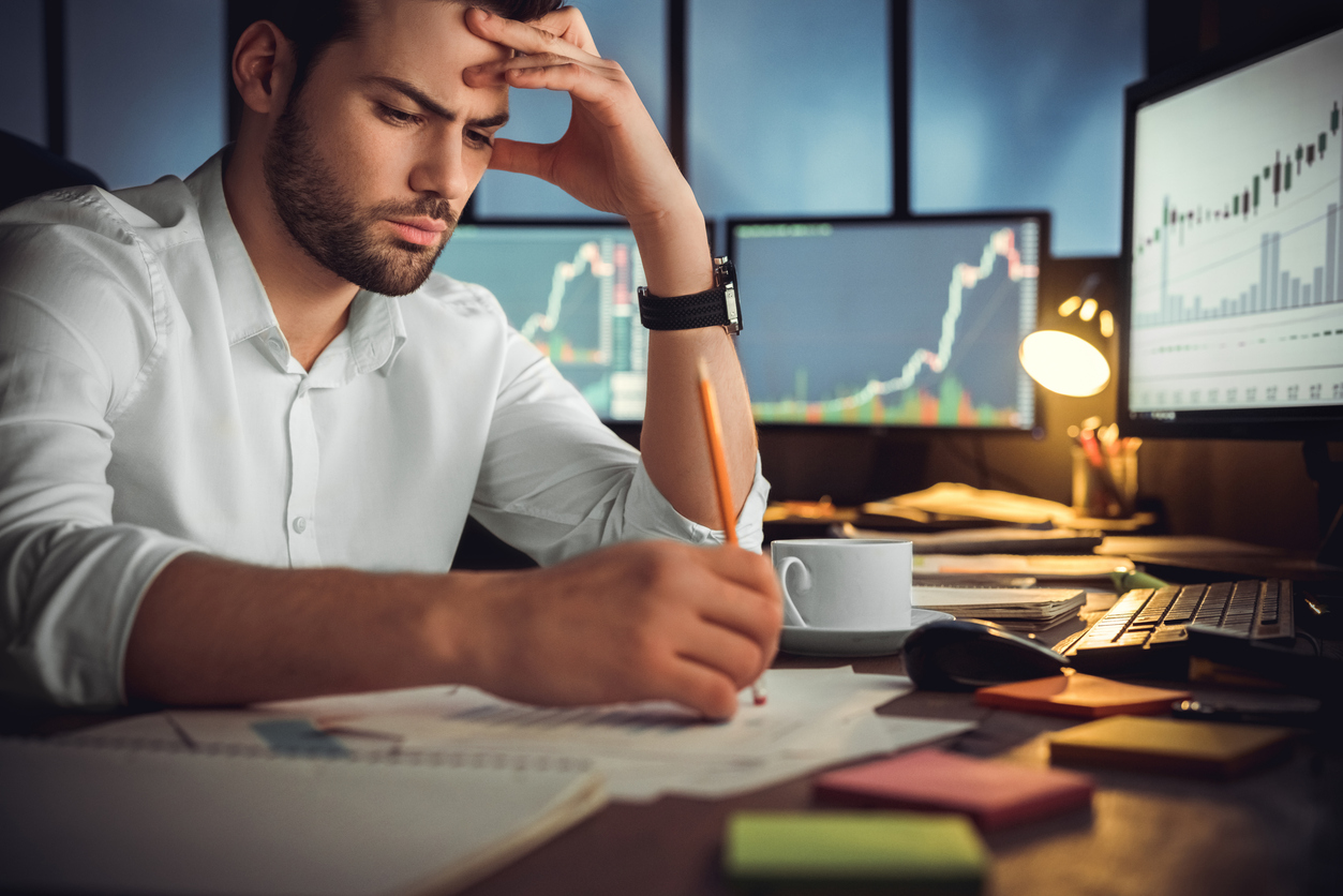 Serious businessman thinking hard of problem solution working late in office with computers documents, thoughtful trader focused on stock trading data analysis, analyzing forecasting financial rates